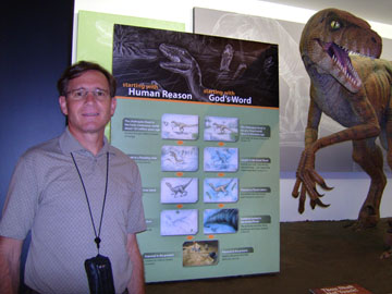 The author poses beside a display comparing "Human Reason" and "God's Word."