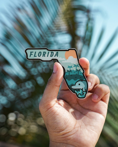 Person holding up a Florida-shaped souvenir.