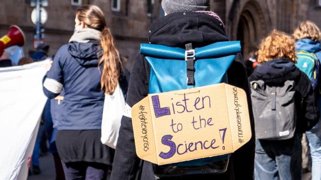 Protester carrrying a "Listen to the Science" poster.