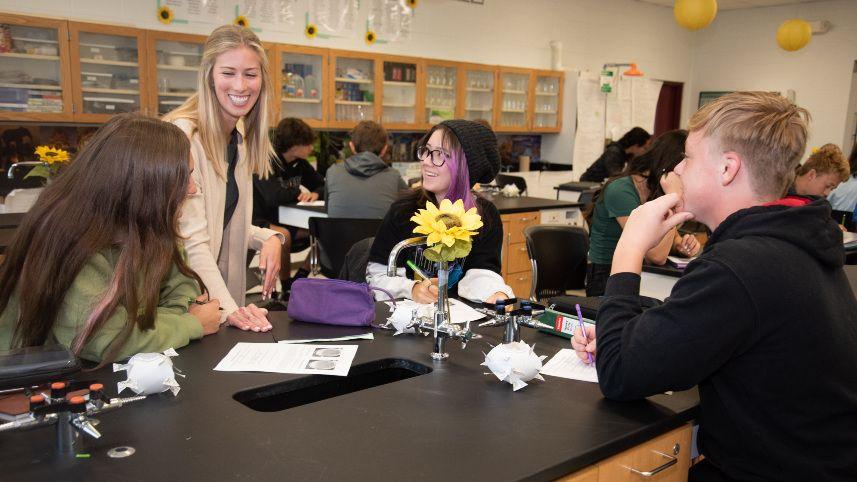Science classroom with teacher and students around a table.